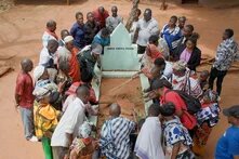 Menschen sind gruppiert um ein Grab