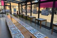 Das Bild zeigt die Comicausstellung "Wie geht es dir?", die auf einer langen Tischreihe ausgelegt ist.