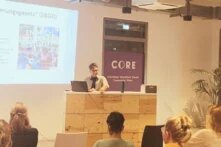 Taleo Stüwe gibt einen Impuls bei der Feministischen Werkstatt in Oldenburg; im Vordergrund: zuhörende Teilnehmer*innen