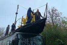 Vier Menschen stehen auf einem Segelboot, das sich auf dem Dach eines Busses befindet