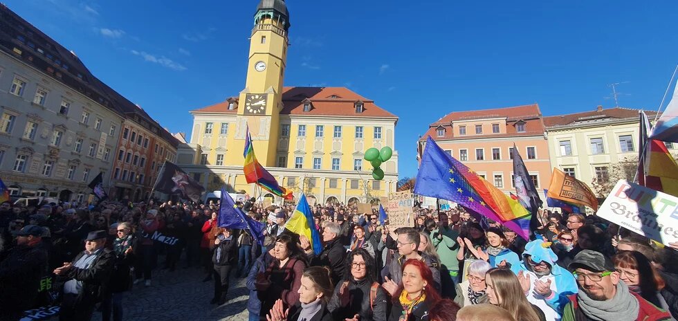 Menschen in Bautzen bei einer Kundgebung mit Regenbogen- und Europafahnen in 2024